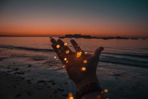 fairy lights person with string lights on left hand beach